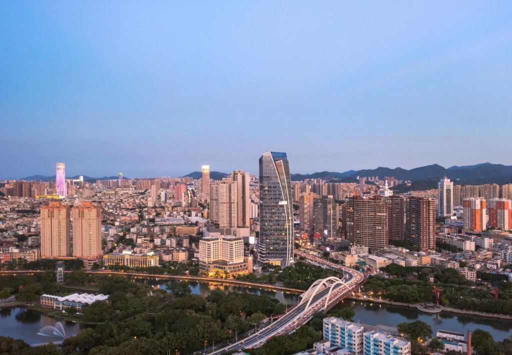 Aerial skyline of Zhongshan City near Zhuhai, featuring modern high rise buildings and the scenic Qijiang River bridge at dusk