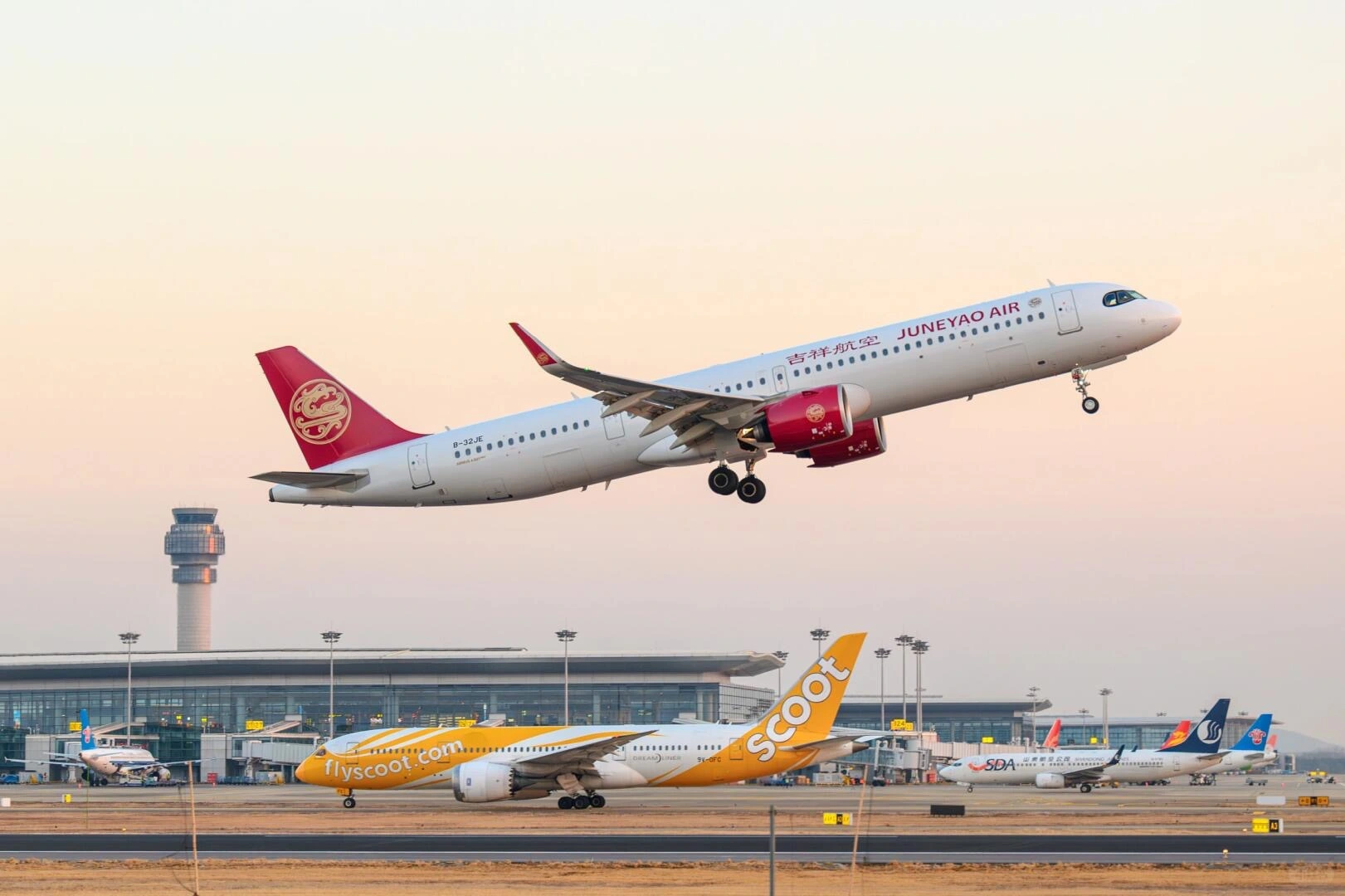 Despegue del Aeropuerto Internacional de Nanjing Lukou: avión comercial despegando del Aeropuerto Internacional de Nanjing Lukou al atardecer, con los edificios de la terminal y la pista al fondo.
