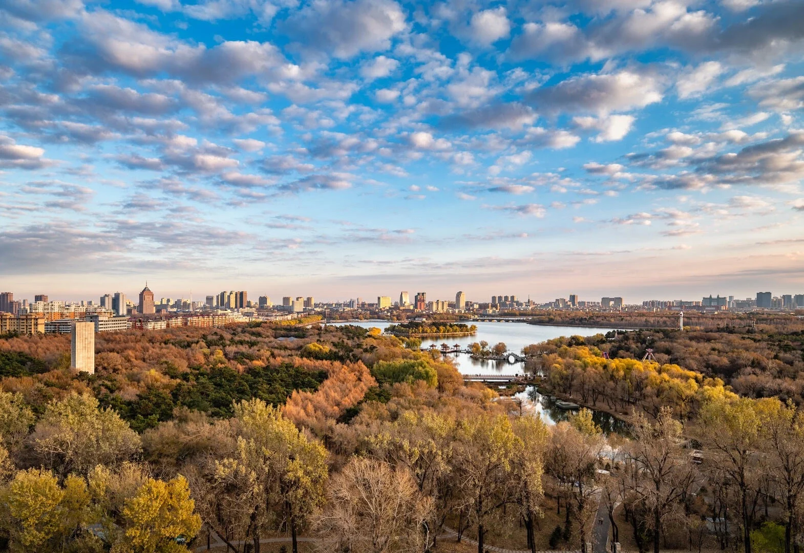 Jingyuetan National Forest Park – Panoramic view of forest, lake, and city skyline in the distance, showing Changchun’s largest urban forest park in autumn colors - Where to Stay in Changchun: Best Areas & Hotels 2026 - The China Journey Jingyuetan National Forest Park – Panoramic view of forest, lake, and city skyline in the distance, showing Changchun’s largest urban forest park in autumn colors - Where to Stay in Changchun: Best Areas & Hotels 2026 - The China Journey