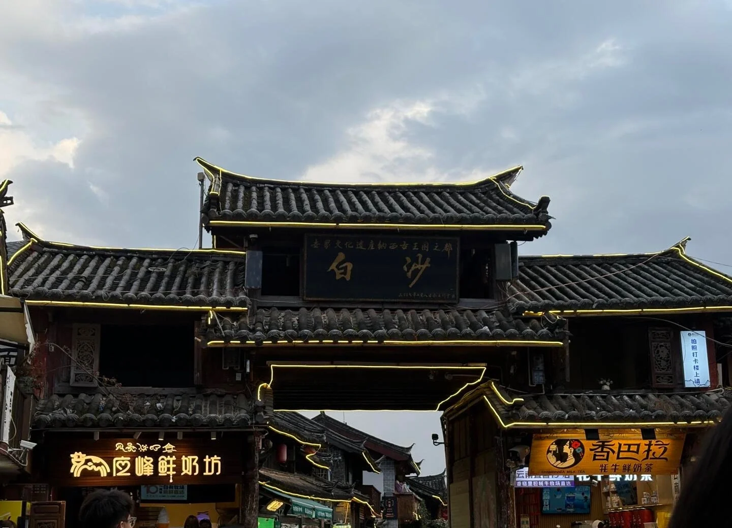 Baisha Ancient Town Gate – historic wooden gate and lively street market in traditional Naxi village - Where to Stay in Lijiang: Best Areas & Hotels 2026 - The China Journey Baisha Ancient Town Gate – historic wooden gate and lively street market in traditional Naxi village - Where to Stay in Lijiang: Best Areas & Hotels 2026 - The China Journey