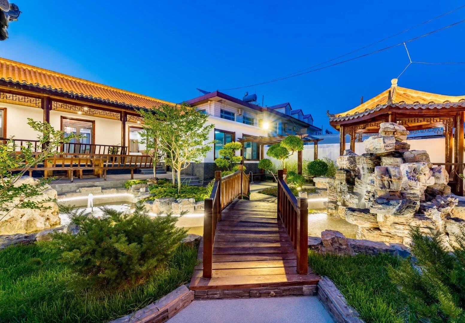 Tuin van een binnenplaatshomestay in Beidaihe, met een traditioneel gastenverblijf, aangelegde tuin en houten brug bij schemering - Reisgids voor Hebei: beste routes buiten Beijing 2026 - The China Journey Tuin van een binnenplaatshomestay in Beidaihe, met een traditioneel gastenverblijf, aangelegde tuin en houten brug bij schemering - Reisgids voor Hebei: beste routes buiten Beijing 2026 - The China Journey