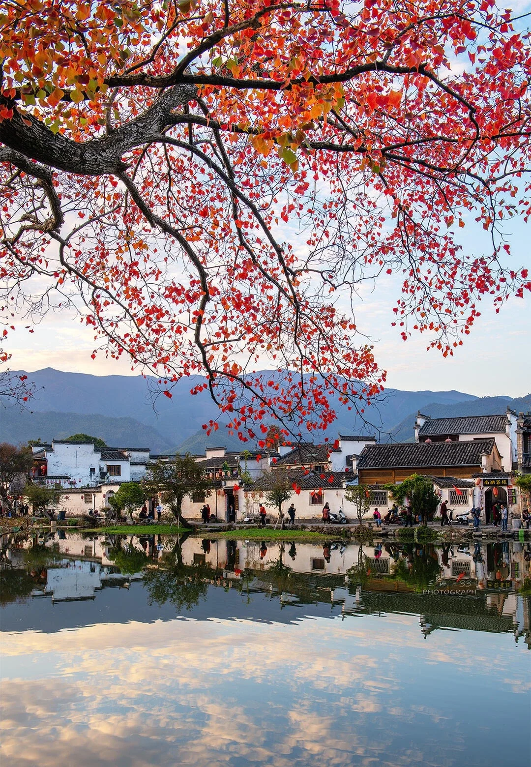 Riflessi sul Lago Nanhu a Hongcun Edifici storici del villaggio riflessi nel lago calmo con foglie autunnali rosse e montagne - Guida di viaggio dell'Anhui: itinerari, consigli e percorsi 2026 - The China Journey Riflessi sul Lago Nanhu a Hongcun Edifici storici del villaggio riflessi nel lago calmo con foglie autunnali rosse e montagne - Guida di viaggio dell'Anhui: itinerari, consigli e percorsi 2026 - The China Journey