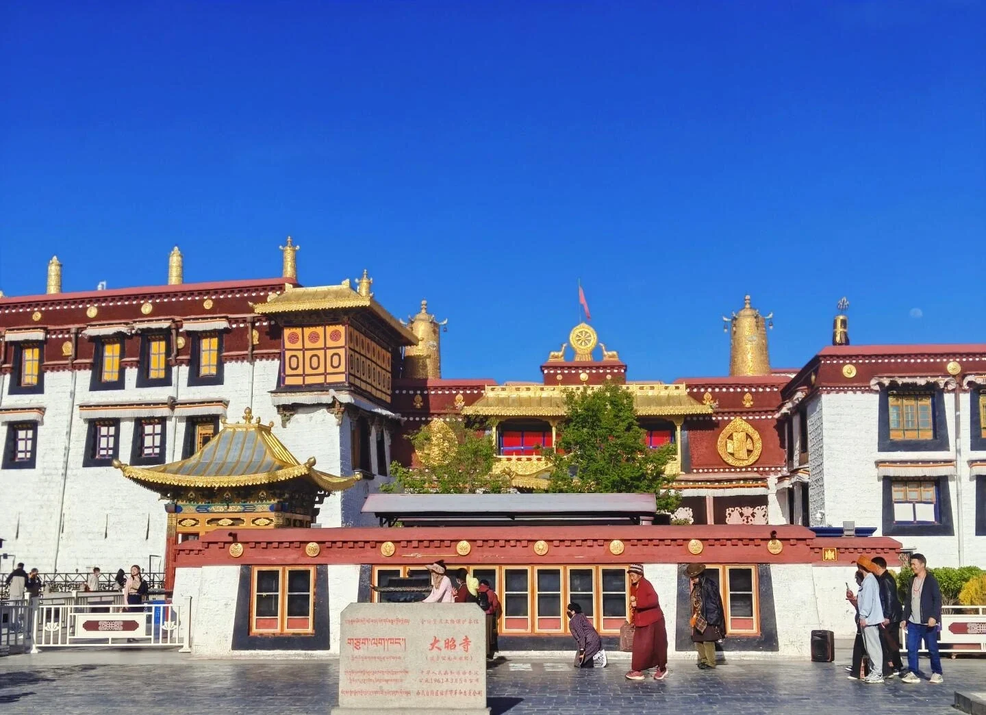 Escena de peregrinación en el Templo de Jokhang con peregrinos tibetanos caminando por el patio sagrado bajo un cielo azul despejado en Lhasa - Guía de viaje al Tíbet: mejores rutas, consejos e itinerarios 2026 - The China Journey Escena de peregrinación en el Templo de Jokhang con peregrinos tibetanos caminando por el patio sagrado bajo un cielo azul despejado en Lhasa - Guía de viaje al Tíbet: mejores rutas, consejos e itinerarios 2026 - The China Journey