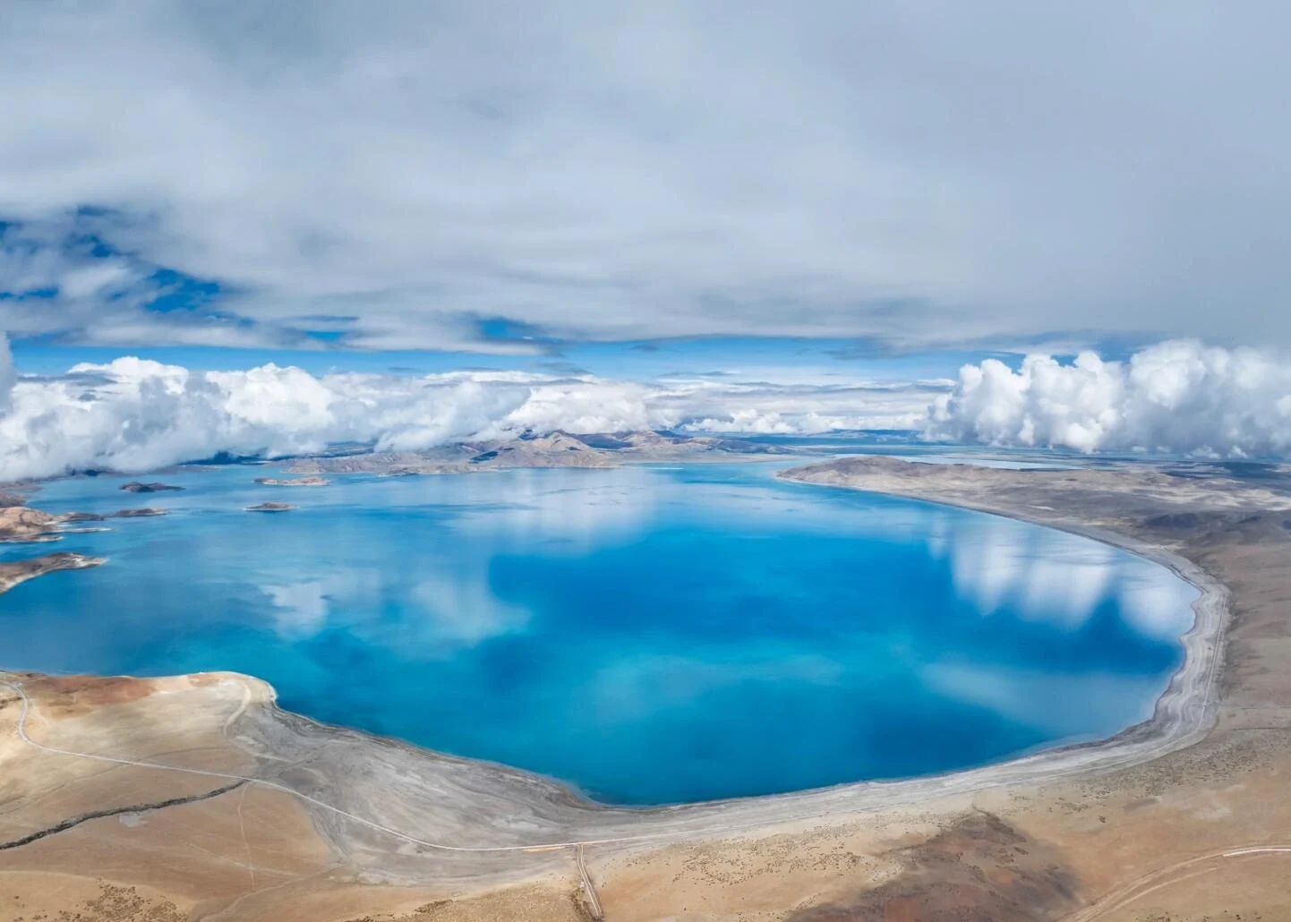 Panorama aéreo del lago Manasarovar, lago sagrado de aguas azules cristalinas rodeado por una meseta árida y nubes flotantes en el oeste del Tíbet - Guía de viaje al Tíbet: mejores rutas, consejos e itinerarios 2026 - The China Journey Panorama aéreo del lago Manasarovar, lago sagrado de aguas azules cristalinas rodeado por una meseta árida y nubes flotantes en el oeste del Tíbet - Guía de viaje al Tíbet: mejores rutas, consejos e itinerarios 2026 - The China Journey