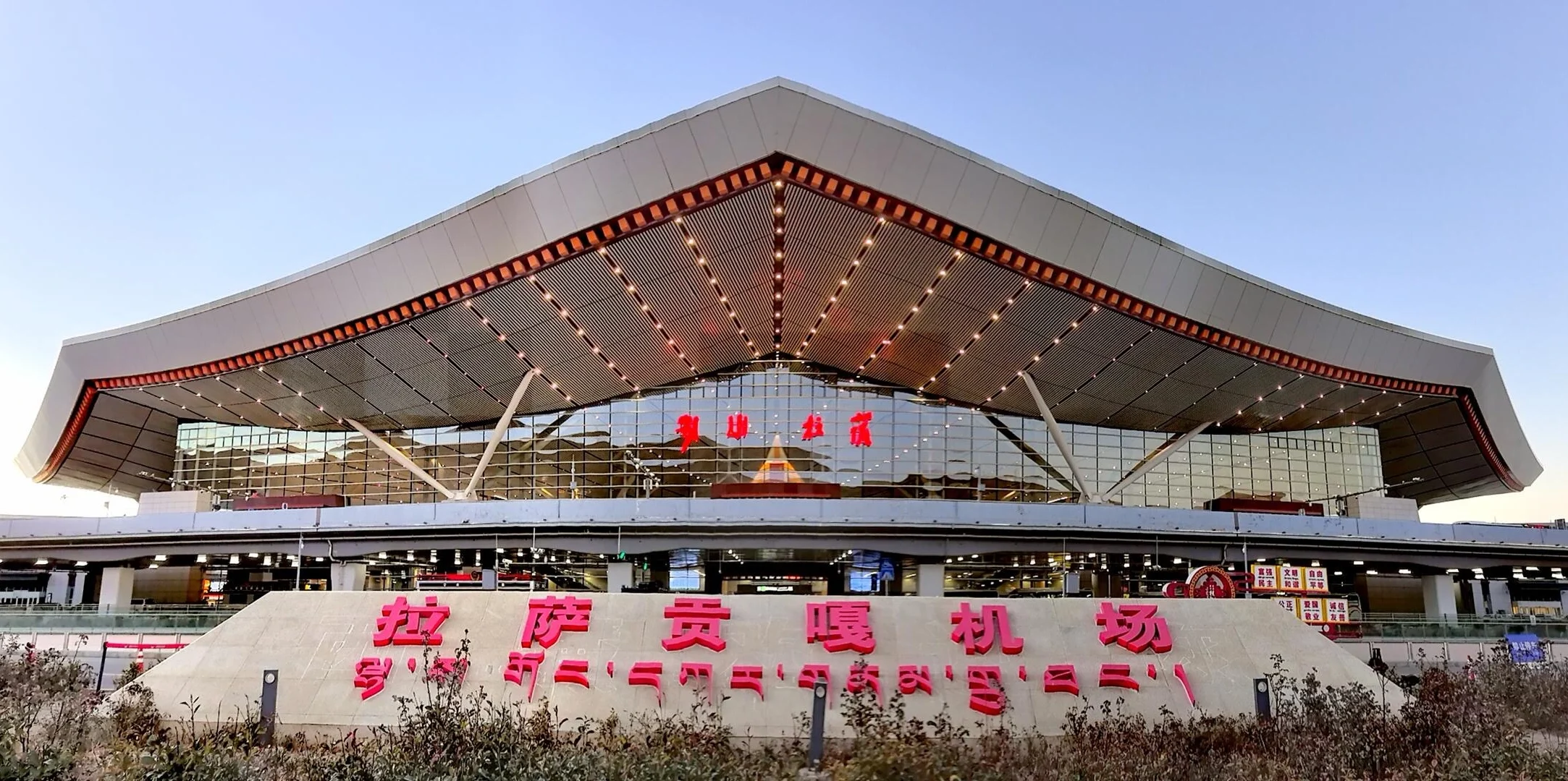 Exterior del aeropuerto de Lhasa Gonggar, moderna terminal de estilo tibetano con tejado tradicional bajo un cielo despejado - Guía de viaje al Tíbet: mejores rutas, consejos e itinerarios 2026 - The China Journey Exterior del aeropuerto de Lhasa Gonggar, moderna terminal de estilo tibetano con tejado tradicional bajo un cielo despejado - Guía de viaje al Tíbet: mejores rutas, consejos e itinerarios 2026 - The China Journey
