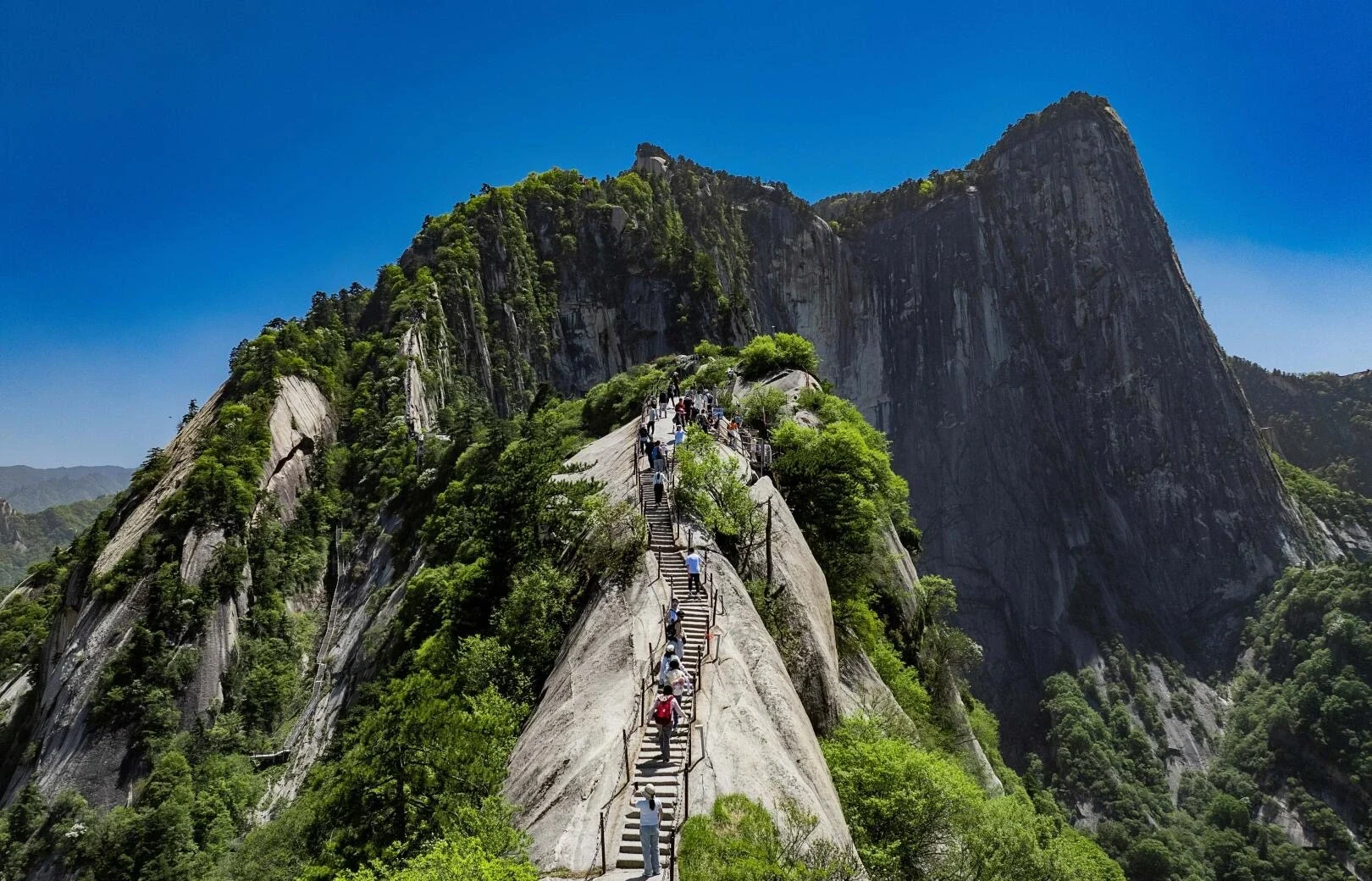 Mount Huashan North Peak hikers climbing narrow ridge trail in summer sunlight - Mount Huashan Travel Guide: Best Routes, Tips & Day Trip 2026 - The China Journey Mount Huashan North Peak hikers climbing narrow ridge trail in summer sunlight - Mount Huashan Travel Guide: Best Routes, Tips & Day Trip 2026 - The China Journey
