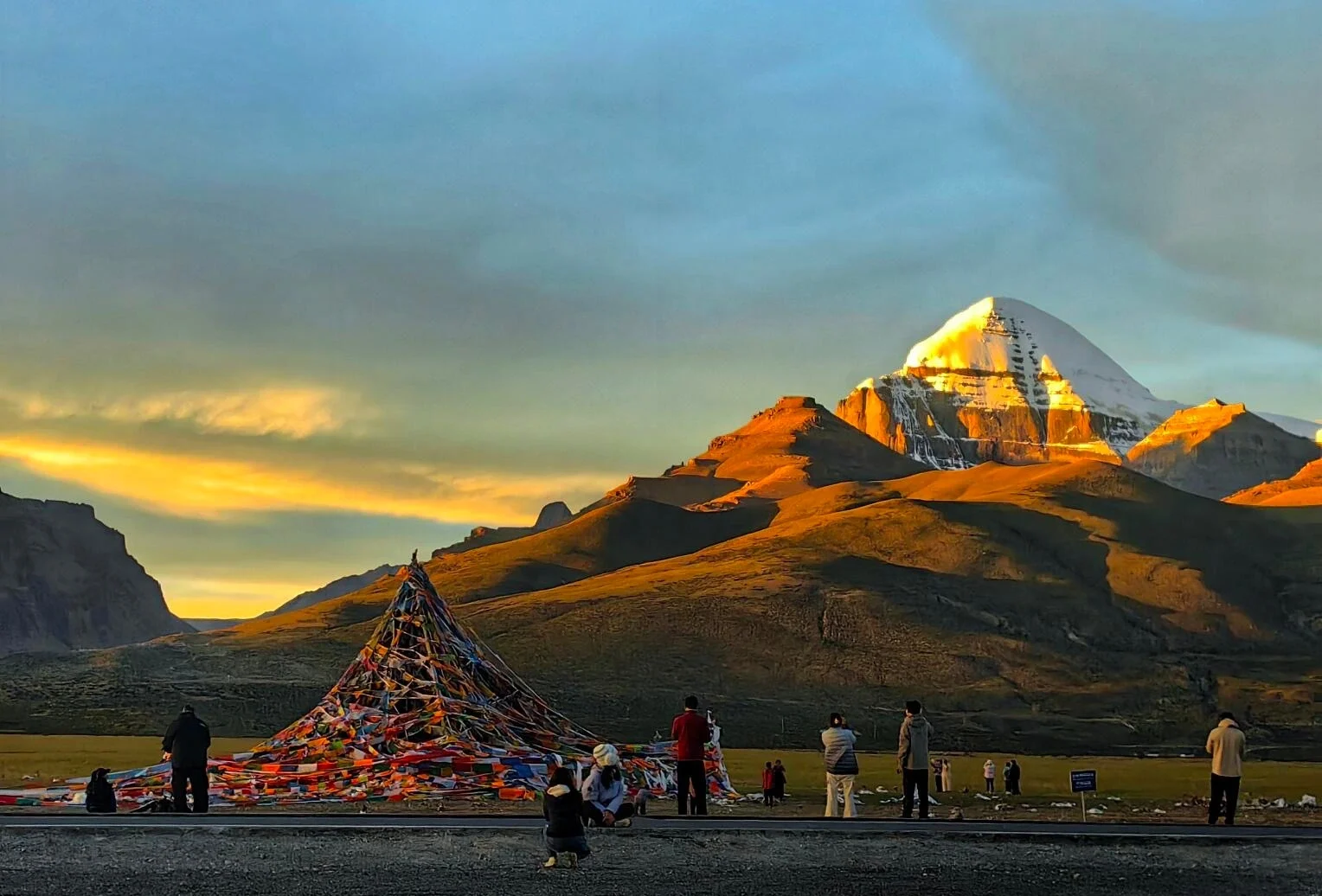 Lugar de peregrinación del monte Kailash al atardecer, con la montaña sagrada iluminada por una luz dorada, peregrinos y banderas de oración en primer plano - Guía de viaje al Tíbet: mejores rutas, consejos e itinerarios 2026 - The China Journey Lugar de peregrinación del monte Kailash al atardecer, con la montaña sagrada iluminada por una luz dorada, peregrinos y banderas de oración en primer plano - Guía de viaje al Tíbet: mejores rutas, consejos e itinerarios 2026 - The China Journey