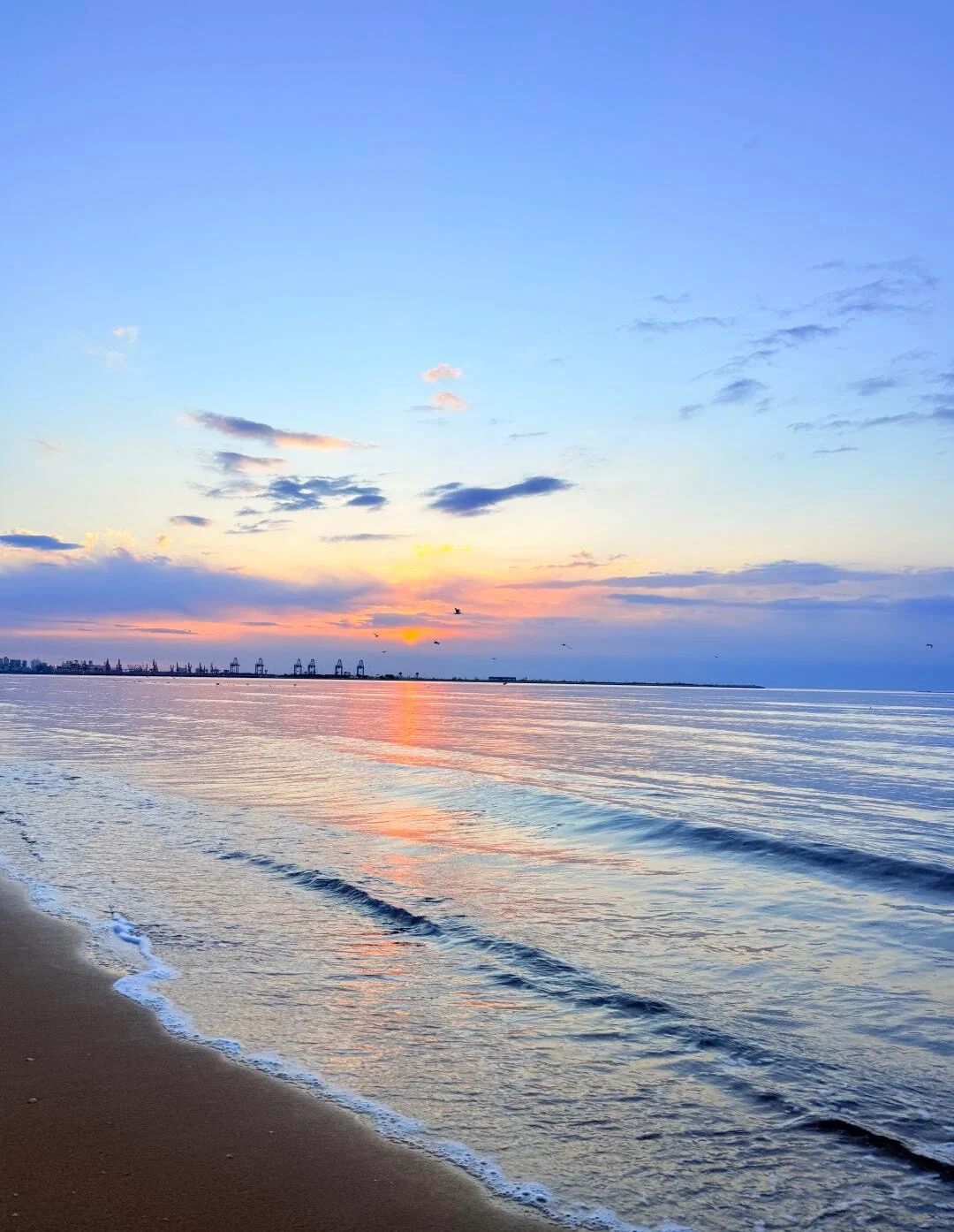 Zonsopgang aan het strand van Qinhuangdao met rustige golven, een gouden hemel en een havensilhouet in de verte - Reisgids voor Hebei: beste routes buiten Beijing 2026 - The China Journey Zonsopgang aan het strand van Qinhuangdao met rustige golven, een gouden hemel en een havensilhouet in de verte - Reisgids voor Hebei: beste routes buiten Beijing 2026 - The China Journey