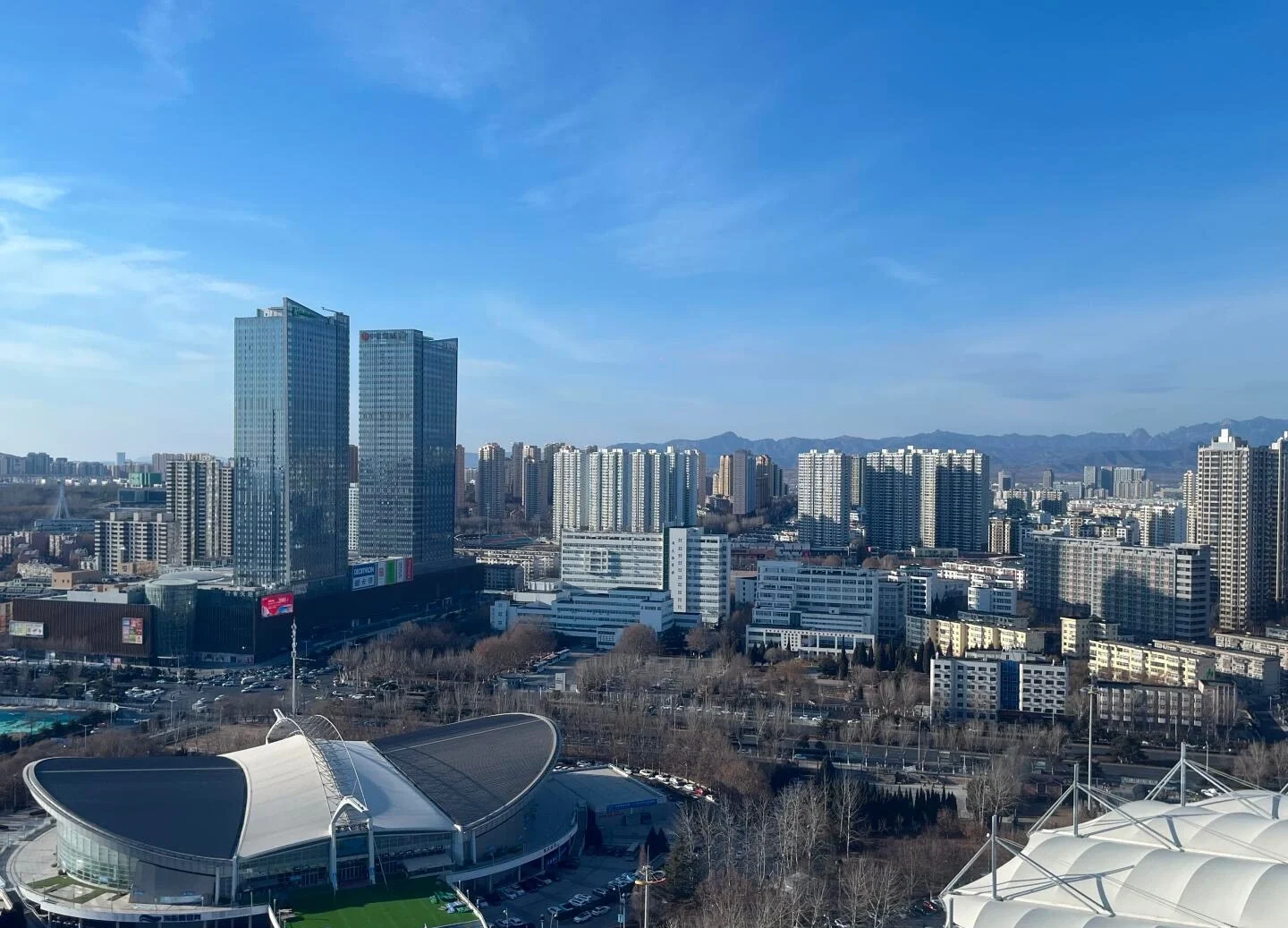 Panorama van de stedelijke skyline van Qinhuangdao met moderne hoogbouw en een stadioncomplex onder een heldere hemel - Reisgids voor Hebei: beste routes buiten Beijing 2026 - The China Journey Panorama van de stedelijke skyline van Qinhuangdao met moderne hoogbouw en een stadioncomplex onder een heldere hemel - Reisgids voor Hebei: beste routes buiten Beijing 2026 - The China Journey