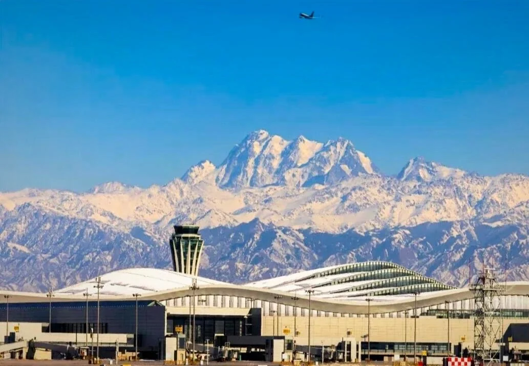 Tianshan Havalimanı ve Karlı Dağlar – etkileyici karla kaplı Tianshan zirvelerinin önündeki modern Xinjiang havalimanı terminali - Xinjiang Seyahat Rehberi: En İyi Rotalar ve Yerler 2026 - Çin Yolculuğu Tianshan Havalimanı ve Karlı Dağlar – etkileyici karla kaplı Tianshan zirvelerinin önündeki modern Xinjiang havalimanı terminali - Xinjiang Seyahat Rehberi: En İyi Rotalar ve Yerler 2026 - Çin Yolculuğu