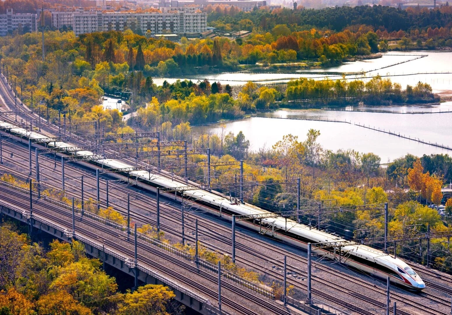 Laluan Kereta Api Laju Wuhan, kereta api peluru merentasi jambatan dengan landskap musim luruh dan tasik di sisi landasan - Panduan Perjalanan Hubei: Laluan, Petua & Jadual Perjalanan 2026 - The China Journey Laluan Kereta Api Laju Wuhan, kereta api peluru merentasi jambatan dengan landskap musim luruh dan tasik di sisi landasan - Panduan Perjalanan Hubei: Laluan, Petua & Jadual Perjalanan 2026 - The China Journey