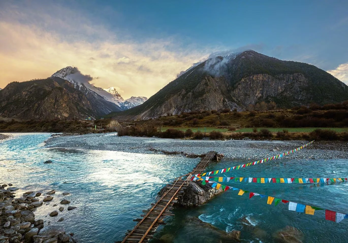 Puente sobre el valle del río Yarlung Tsangpo, con un río turquesa que atraviesa un espectacular valle montañoso, puente de madera y banderas de oración - Guía de viaje al Tíbet: mejores rutas, consejos e itinerarios 2026 - The China Journey Puente sobre el valle del río Yarlung Tsangpo, con un río turquesa que atraviesa un espectacular valle montañoso, puente de madera y banderas de oración - Guía de viaje al Tíbet: mejores rutas, consejos e itinerarios 2026 - The China Journey