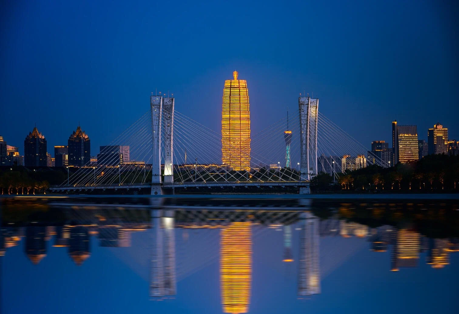 Skyline am Millennium Plaza in Zhengzhou: modern beleuchtete Wolkenkratzer und eine Brücke spiegeln sich nachts in einem ruhigen Fluss – Zhengzhou-Reiseführer: Shaolin, Essen & Tipps 2026 – The China Journey Skyline am Millennium Plaza in Zhengzhou: modern beleuchtete Wolkenkratzer und eine Brücke spiegeln sich nachts in einem ruhigen Fluss – Zhengzhou-Reiseführer: Shaolin, Essen & Tipps 2026 – The China Journey