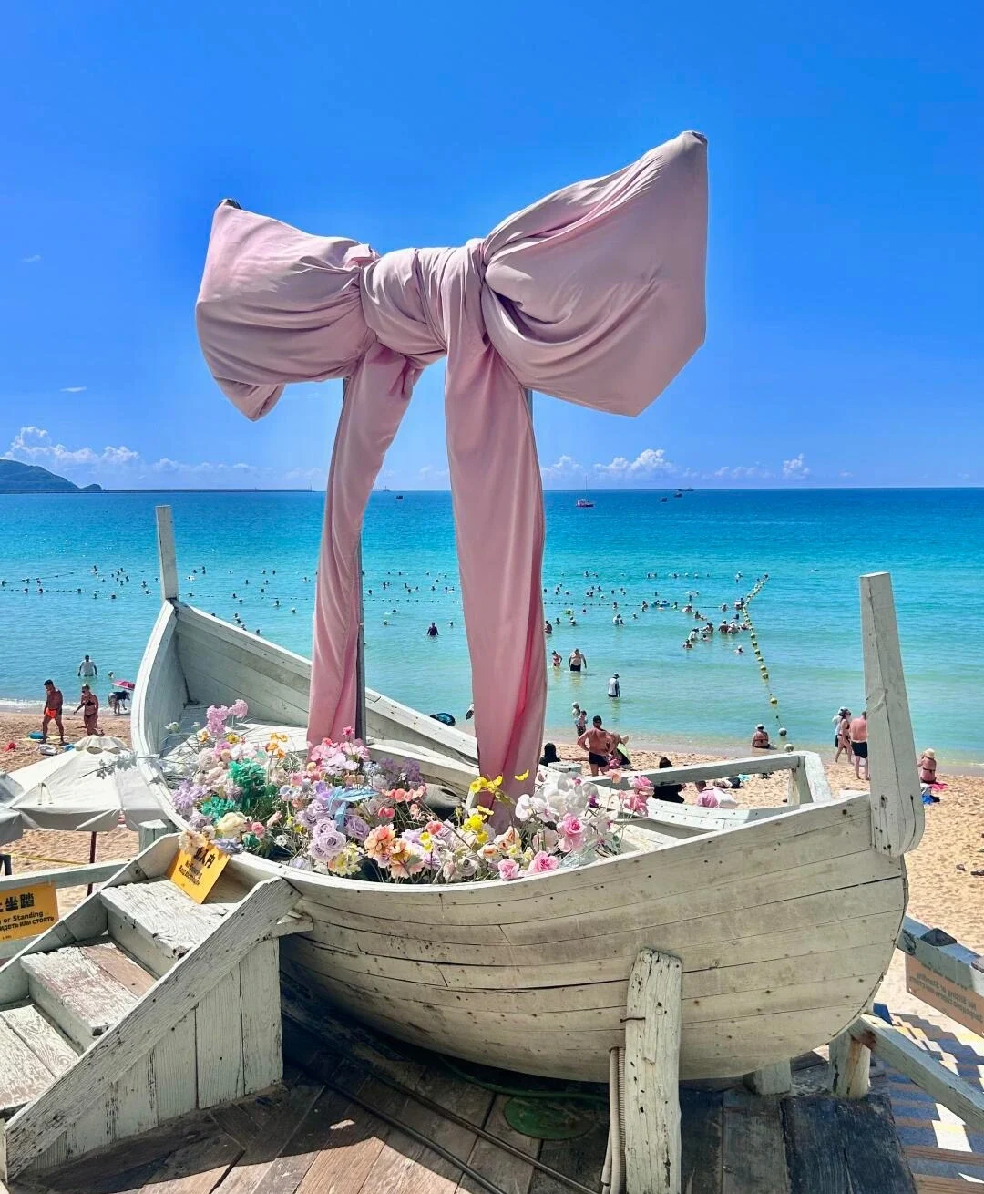 Bootsdekoration am Dadonghai Beach in Sanya mit Holzboot, Blumenarrangement, türkisfarbenem Meer und lebhaftem Strand – Sanya-Reiseführer: Strände, Buchten & Tipps 2026 – The China Journey Bootsdekoration am Dadonghai Beach in Sanya mit Holzboot, Blumenarrangement, türkisfarbenem Meer und lebhaftem Strand – Sanya-Reiseführer: Strände, Buchten & Tipps 2026 – The China Journey