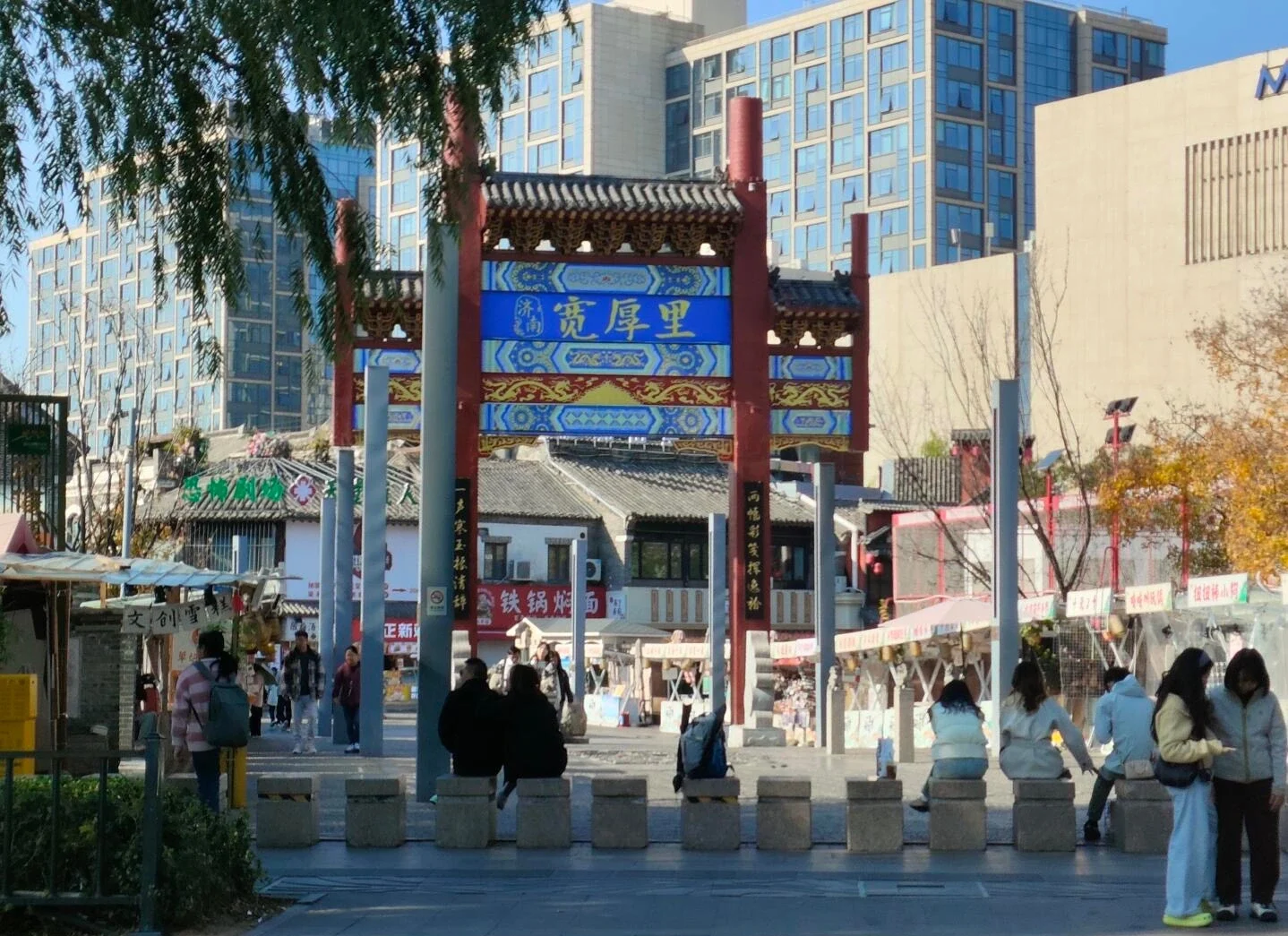 Indgangen til kulturstrøget Kuanhouli, traditionel port ved en travl markedsgade med butikker, besøgende og byliv i Jinan - Jinan rejseguide: Bedste rejseplan og tips 2026 - The China Journey Indgangen til kulturstrøget Kuanhouli, traditionel port ved en travl markedsgade med butikker, besøgende og byliv i Jinan - Jinan rejseguide: Bedste rejseplan og tips 2026 - The China Journey