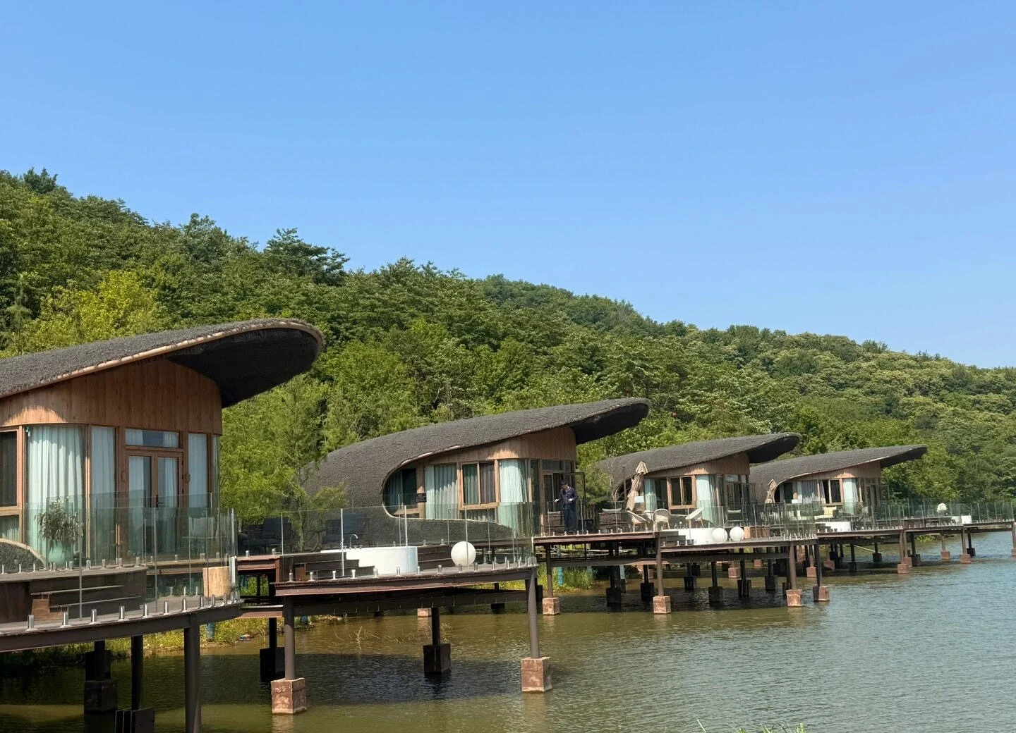 Lujiang Lake House Villas Hefei Unique curved wooden villas on stilts overlooking tranquil lake and green hills