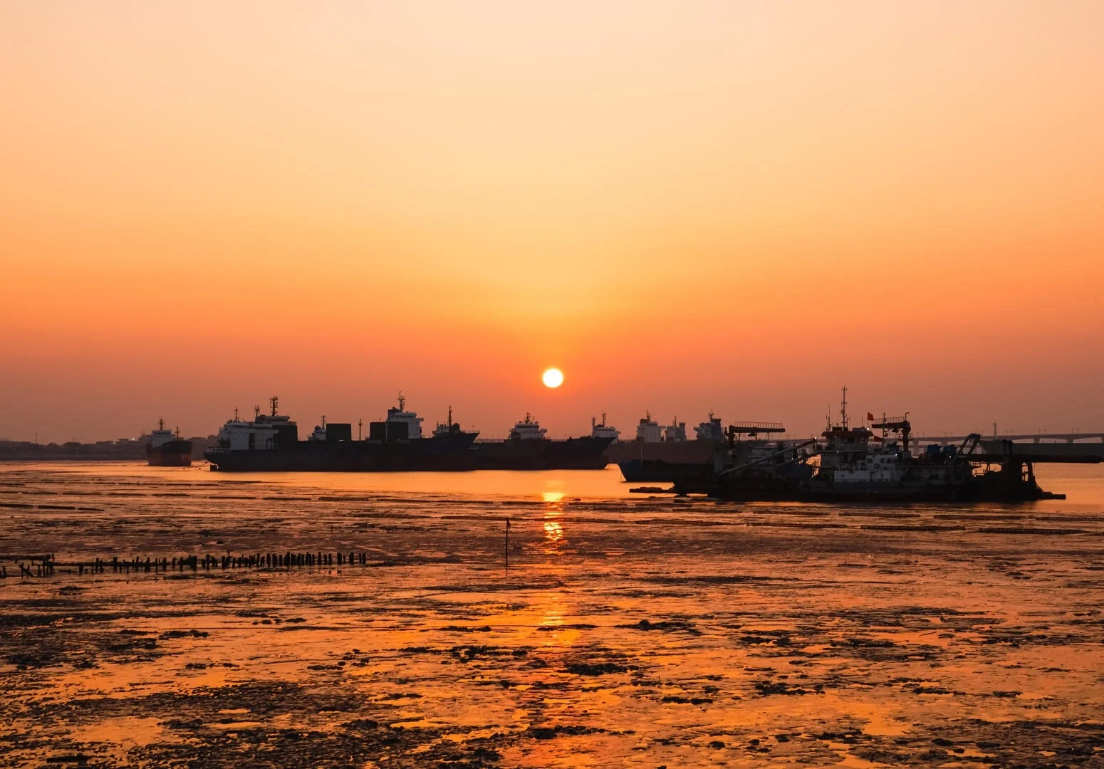 Silhouet van de haven van Quanzhou bij zonsondergang, vrachtschepen en vissersboten tegen oranje licht boven wad en kalm kustwater - Reisgids voor Quanzhou: beste route, eten & tips 2026 - The China Journey Silhouet van de haven van Quanzhou bij zonsondergang, vrachtschepen en vissersboten tegen oranje licht boven wad en kalm kustwater - Reisgids voor Quanzhou: beste route, eten & tips 2026 - The China Journey