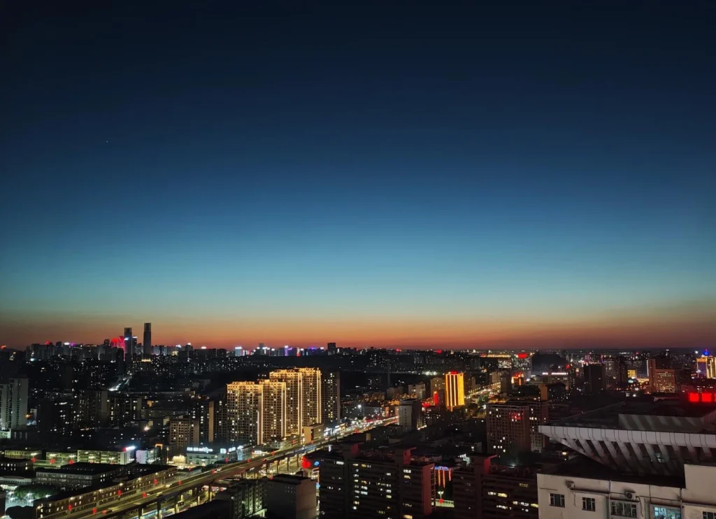 Urumqi City Night Skyline Illuminated urban buildings roads and distant skyline under colorful twilight sky in Xinjiang capital