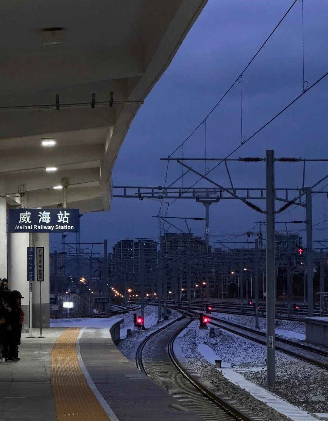 Weihai Railway Station Platform Night Train tracks and station platform at dusk with city lights and quiet atmosphere - Where to Stay in Weihai: Best Areas & Hotels 2026 - The China Journey Weihai Railway Station Platform Night Train tracks and station platform at dusk with city lights and quiet atmosphere - Where to Stay in Weihai: Best Areas & Hotels 2026 - The China Journey