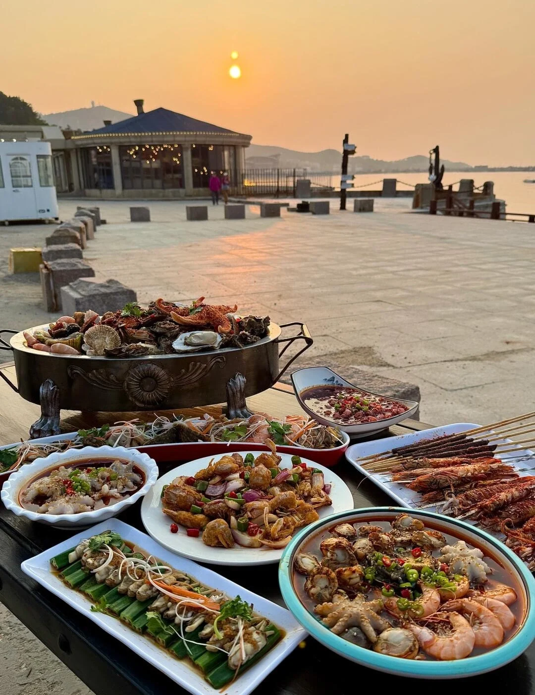 Meeresfrüchtefest in Weihai bei Sonnenuntergang, frische Gerichte auf einem Tisch am Meer im warmen goldenen Licht – Weihai-Reiseführer: Sehenswürdigkeiten, Strände & Tipps 2026 – The China Journey Meeresfrüchtefest in Weihai bei Sonnenuntergang, frische Gerichte auf einem Tisch am Meer im warmen goldenen Licht – Weihai-Reiseführer: Sehenswürdigkeiten, Strände & Tipps 2026 – The China Journey