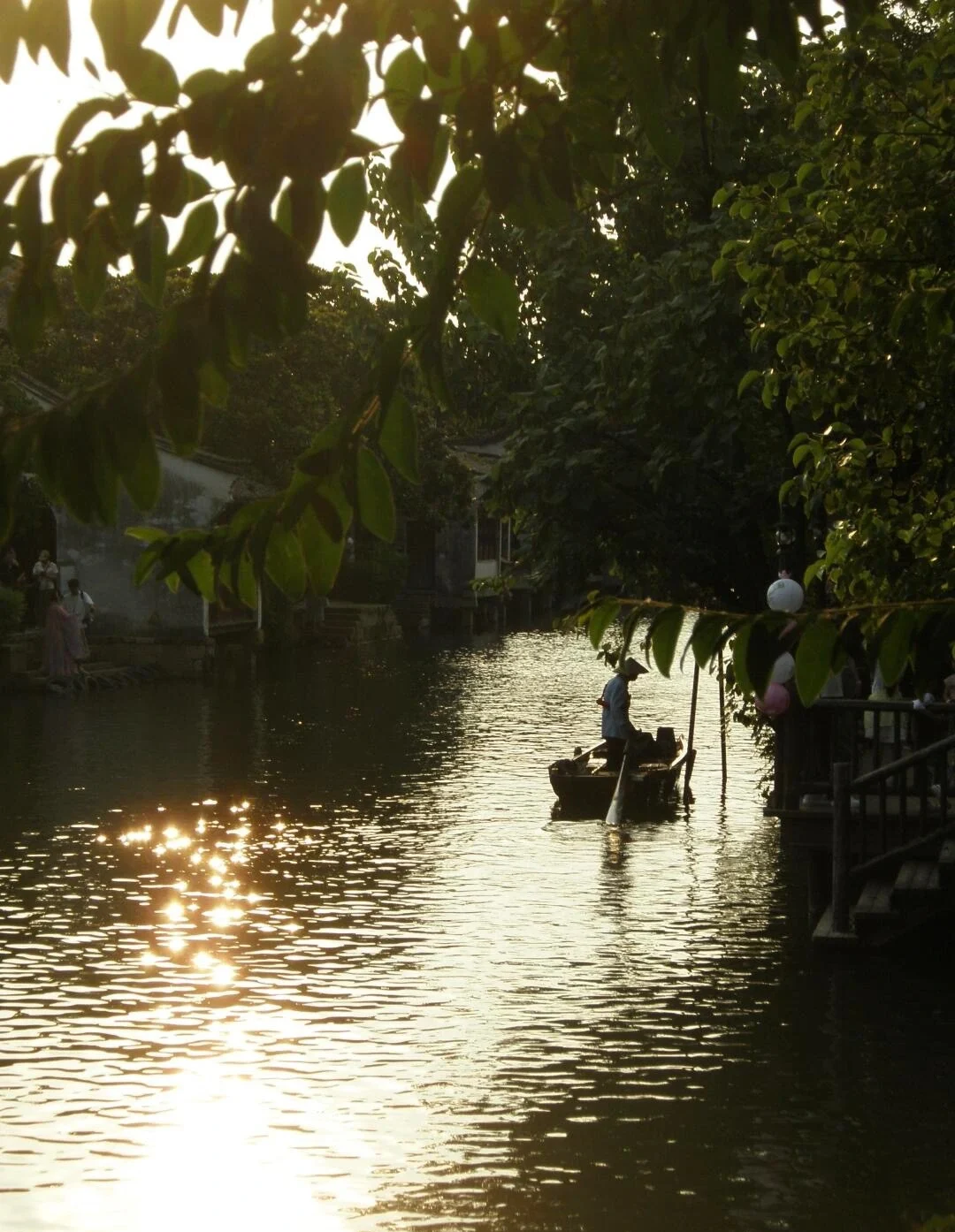 Zomerse zonsondergang aan het kanaal in Wuzhen, met het silhouet van een boot op glinsterend water onder een gouden avondlucht tussen weelderige bomen aan de oever - Reisgids voor Jiaxing: waterstadjes, routes en tips 2026 - The China Journey Zomerse zonsondergang aan het kanaal in Wuzhen, met het silhouet van een boot op glinsterend water onder een gouden avondlucht tussen weelderige bomen aan de oever - Reisgids voor Jiaxing: waterstadjes, routes en tips 2026 - The China Journey