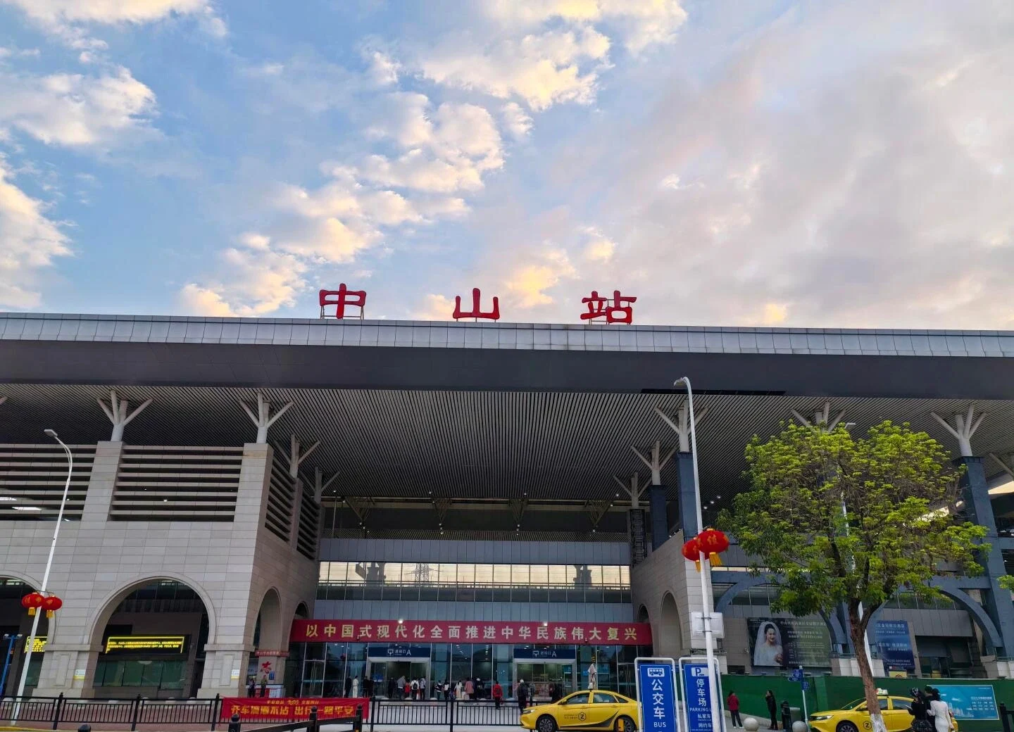 Pintu Masuk Utama Stasiun Kereta Api Zhongshan: Fasad stasiun besar dengan plaza, rambu transportasi, dan arus penumpang - Tempat Menginap di Zhongshan: Area & Hotel Terbaik 2026 - The China Journey Pintu Masuk Utama Stasiun Kereta Api Zhongshan: Fasad stasiun besar dengan plaza, rambu transportasi, dan arus penumpang - Tempat Menginap di Zhongshan: Area & Hotel Terbaik 2026 - The China Journey