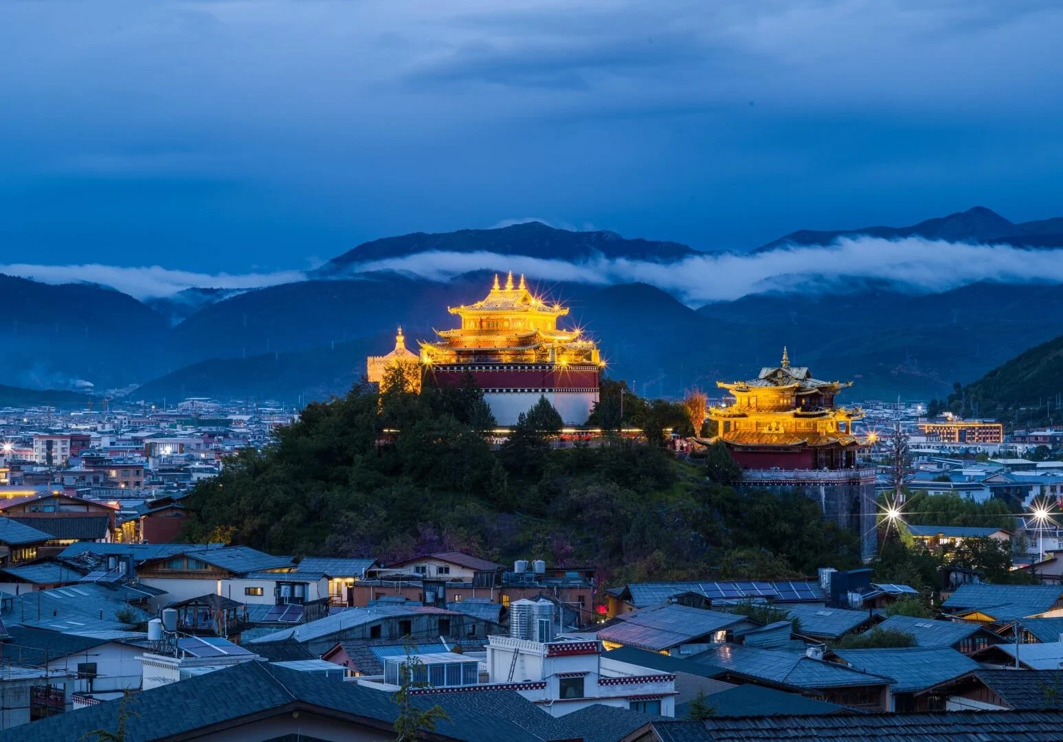 Dukezong Ancient Town Shangri La old town glowing at night below mountain clouds - Where to Stay in Yunnan: Best Areas & Hotels 2026 - The China Journey Dukezong Ancient Town Shangri La old town glowing at night below mountain clouds - Where to Stay in Yunnan: Best Areas & Hotels 2026 - The China Journey